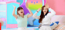 two girls are dancing in front of a rainbow cat