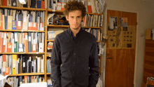 a man in a black shirt stands in front of a bookshelf with a folder that says ' aalborg '