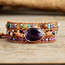 a bracelet with purple beads and a purple stone in the middle