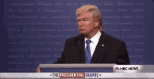 a man in a suit and tie stands in front of a podium that says " the presidential debate "