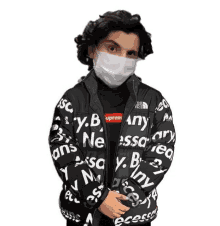 a person wearing a face mask and a jacket that says supreme on it