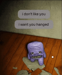 a purple monster is sitting on a wooden floor next to a text that says i don t like you