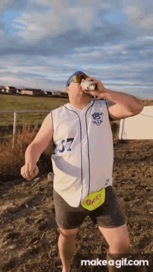 a man wearing a baseball jersey with the number 57 drinking a beer