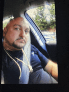 a bald man with a beard is sitting in a car