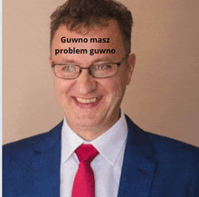 a man wearing glasses and a blue suit has a sticker on his forehead that reads " gwno masz problem gwno "