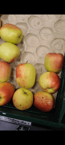 a bunch of apples are sitting on a cardboard tray with a label that says " nieder da "