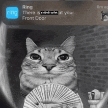 a cat is holding a fan of money in front of a toilet and a ring notification