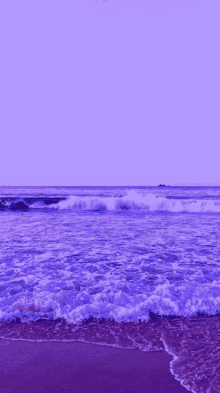 a purple ocean with waves crashing on a sandy beach