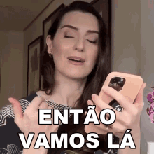 a woman is holding a cell phone with the words entao vamos la written on it