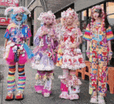 a group of girls wearing colorful clothes are standing on a sidewalk in front of a building with chinese characters on it