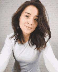 a woman wearing a white shirt looks at the camera