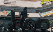 a man stands in front of a car in front of a hair & nails store