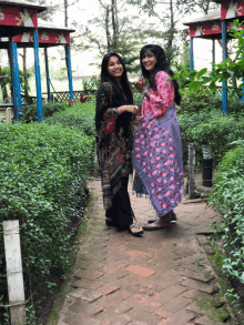 two women are standing next to each other on a brick walkway in front of a gazebo with a coca cola logo on it