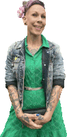 a woman wearing a green dress and a denim jacket has a tattoo on her arm