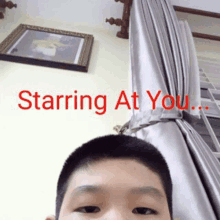 a young boy is taking a selfie in front of a wall with the words starring at you .