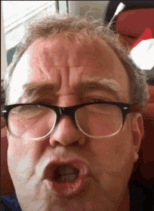 a man with glasses making a funny face with his mouth open