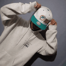 a person wearing a miami dolphins hat and a hoodie