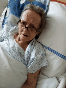 an elderly woman in a hospital bed wearing glasses