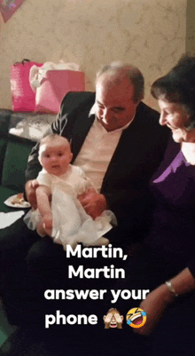 a man in a suit is holding a baby with the caption " martin martin answer your phone " below him