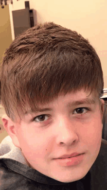 a close up of a boy 's face with a gray shirt on