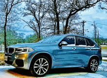 a blue bmw is parked in the snow in front of trees