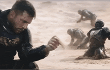 a man in armor is kneeling in the sand with a skull on his chest