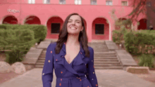 a woman in a blue dress is smiling in front of a red building that says rtve.es on the bottom