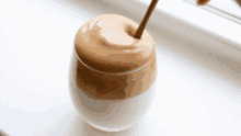 a glass of whipped coffee with a wooden spoon in it