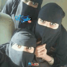 three women wearing black hijabs are posing for a picture .