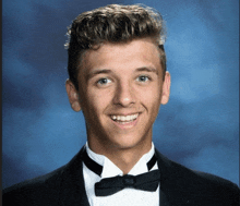 a young man wearing a tuxedo and bow tie smiles for a picture