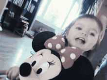 a little girl holding a minnie mouse stuffed animal