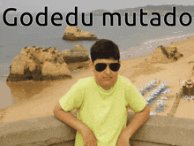 a boy wearing sunglasses stands on a balcony overlooking a beach with the words godedu mutato on the bottom