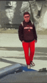 a man wearing red pants and a sweatshirt that says carnival