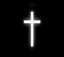 a white cross is glowing in the dark against a black background .