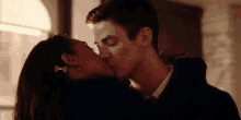 a man and a woman are kissing in front of a window in a room .