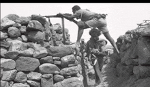 a black and white photo of soldiers in a rocky area