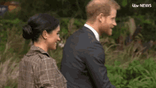 a man in a suit and a woman in a plaid jacket are talking to each other in front of an itv news headline