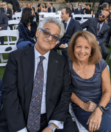 a man in a suit and tie sitting next to a woman in a blue dress