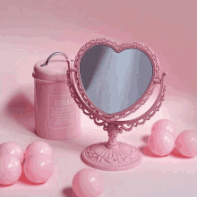 a pink heart shaped mirror is surrounded by pink balls and a pink sugar can