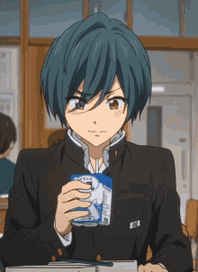 a boy with blue hair is sitting at a table holding a can of milk