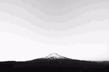 a black and white photo of a mountain with a white sky in the background