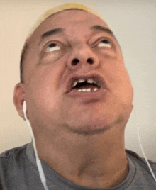 a man with no teeth is wearing ear buds and making a funny face .