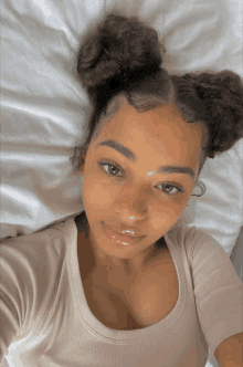 a woman is laying on a bed with her hair in two buns