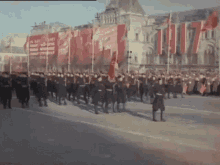 a group of people marching down a street in front of a building with flags that say ' soviet union ' on them