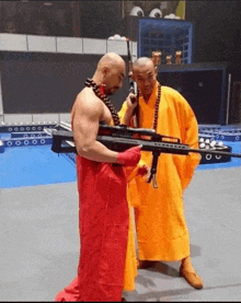 a man in a yellow robe is holding a gun next to another man