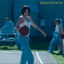 a woman in a white tank top is holding a basketball in front of a sign that says " wentworth "