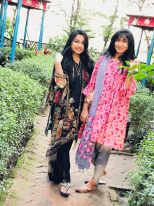 two women are standing next to each other on a brick walkway