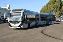 a very long bus is parked in a parking lot .