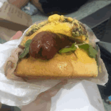 a close up of a person holding a sandwich with a sausage on top