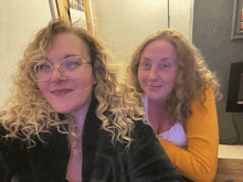 two women with curly hair are posing for a photo